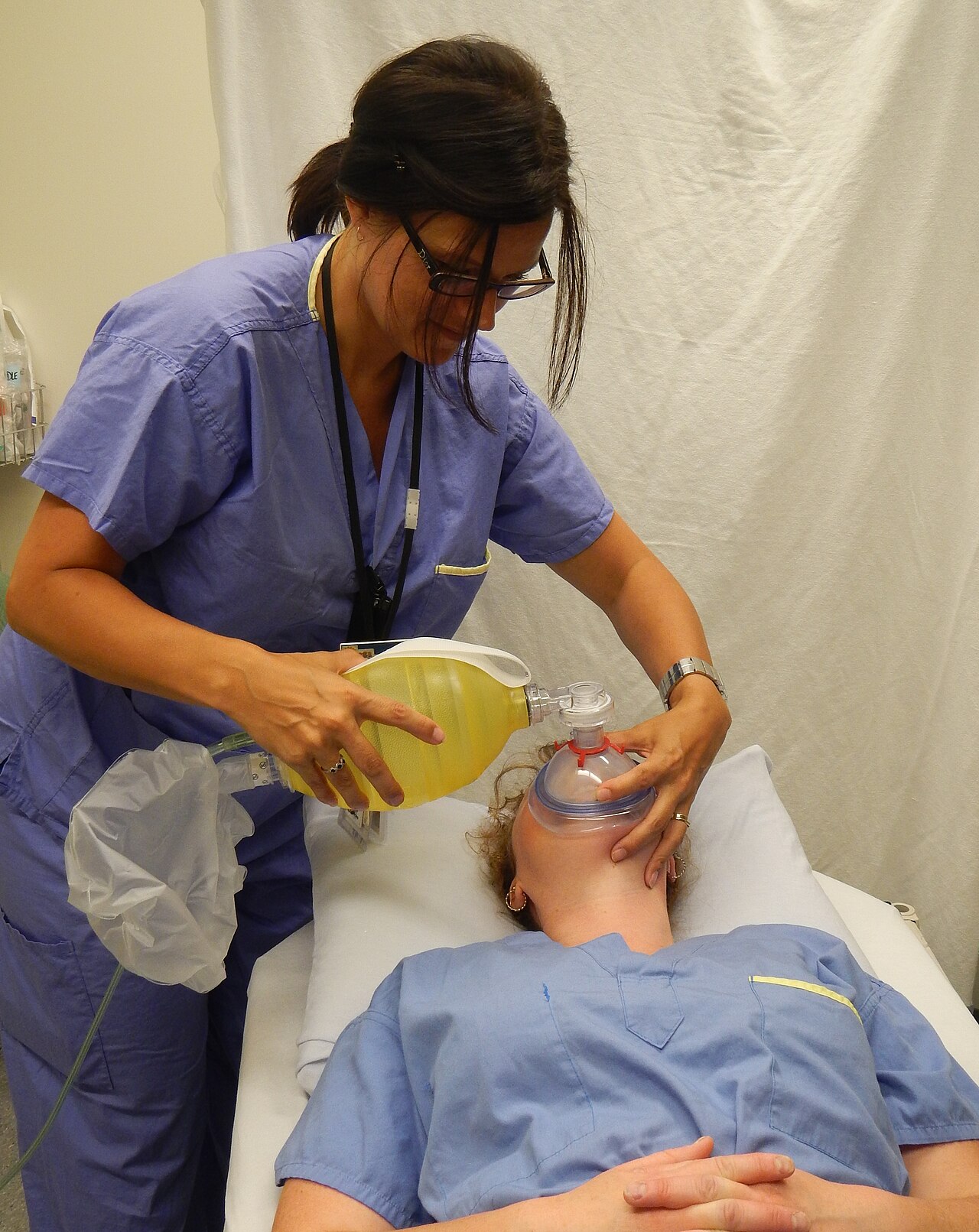 Single rescuer holding a face mask with one hand while squeezing a bag-valve-mask device