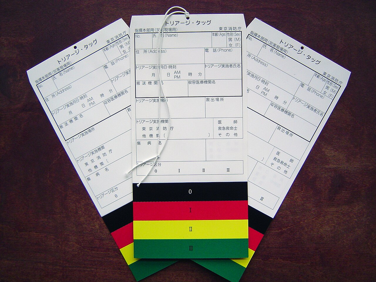 Japanese triage tags in black 0, red I, yellow II and green III categories, with fields for name, time and transport