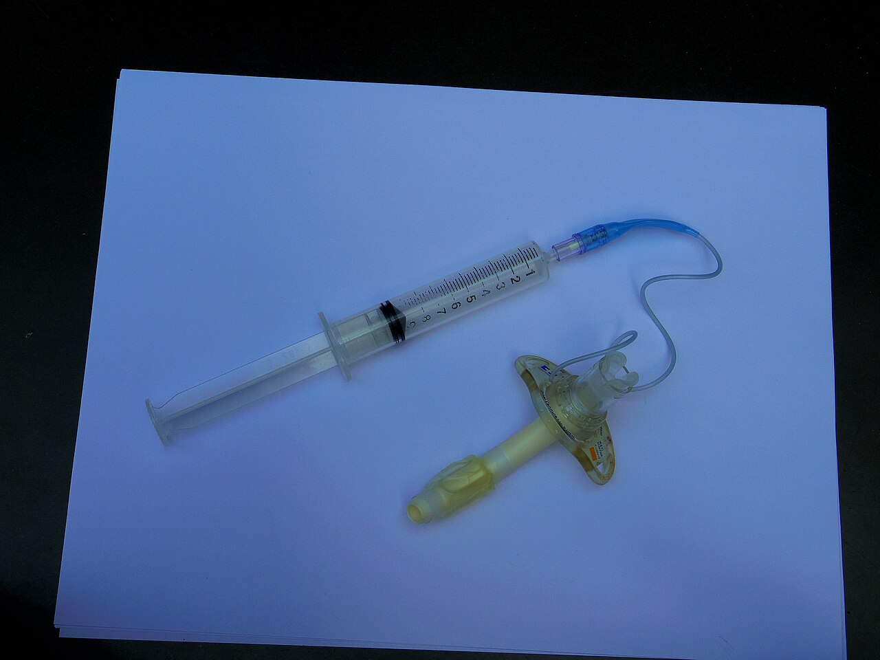Cuffed tracheostomy tube with a syringe attached to the pilot balloon to inflate the cuff