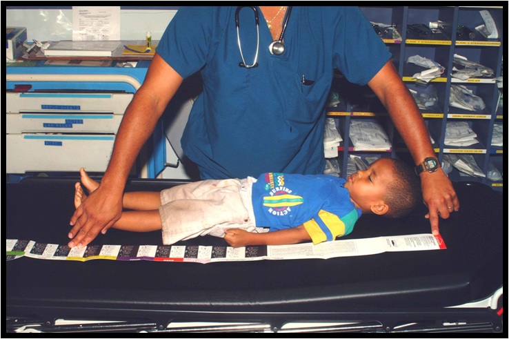 Child lying supine on a stretcher with the Broselow tape laid from head to heel along the body